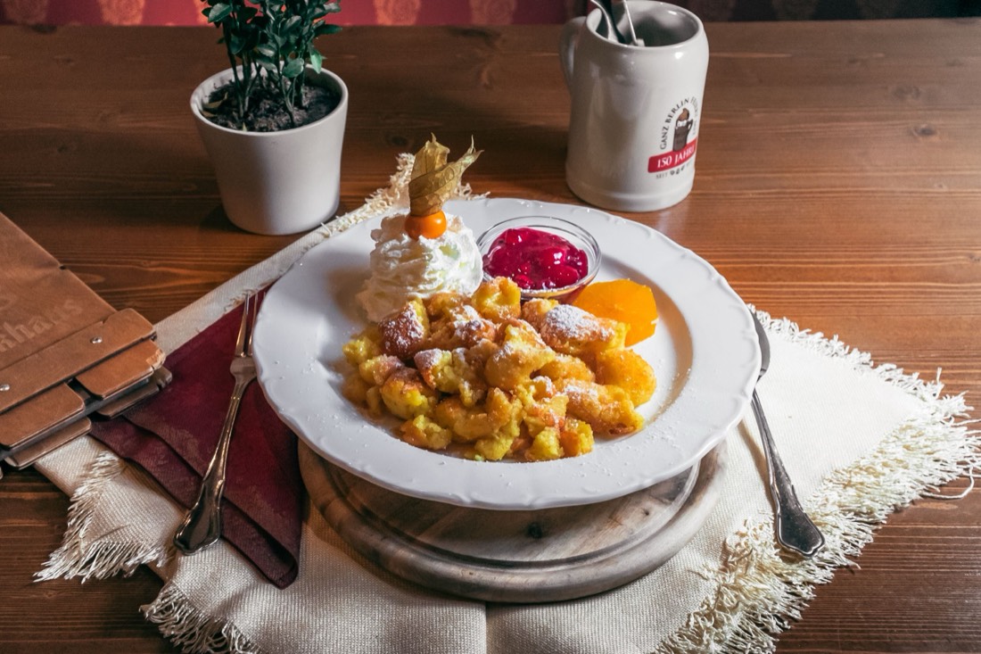 Kaiserschmarrn frisch aus der Pfanne mit Puderzucker, Fruchtkompott und Sahne